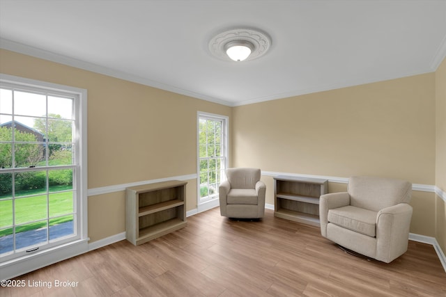 sitting room with light wood-style floors, ornamental molding, and baseboards