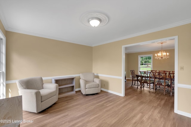 living area featuring a notable chandelier, ornamental molding, light wood finished floors, and baseboards