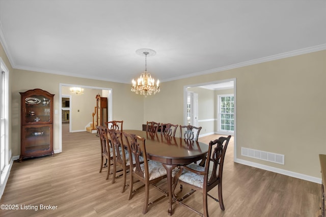 dining area featuring visible vents, ornamental molding, a notable chandelier, and light wood-style floors