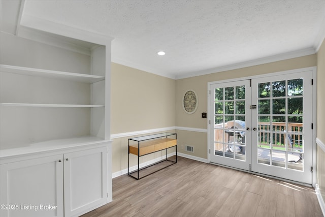 doorway to outside featuring a textured ceiling, french doors, light wood-type flooring, and crown molding