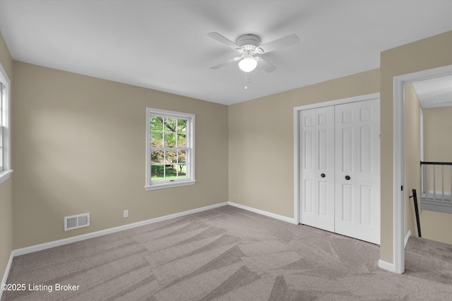 unfurnished bedroom with a closet, ceiling fan, carpet flooring, baseboards, and visible vents