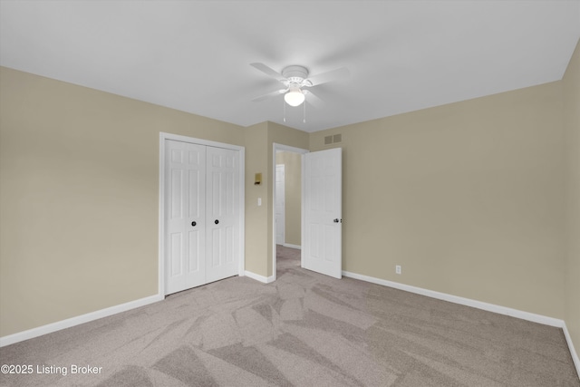 unfurnished bedroom with a closet, ceiling fan, visible vents, carpet, and baseboards