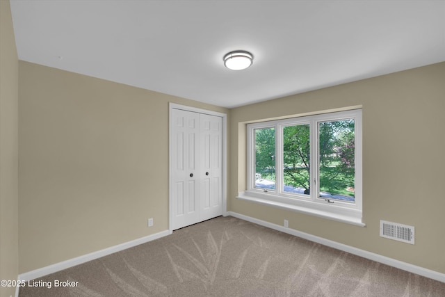 carpeted empty room with visible vents and baseboards