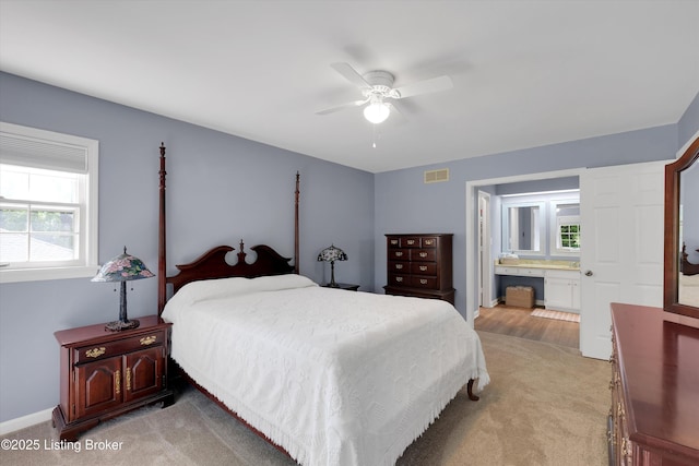 bedroom with connected bathroom, light colored carpet, visible vents, baseboards, and a ceiling fan