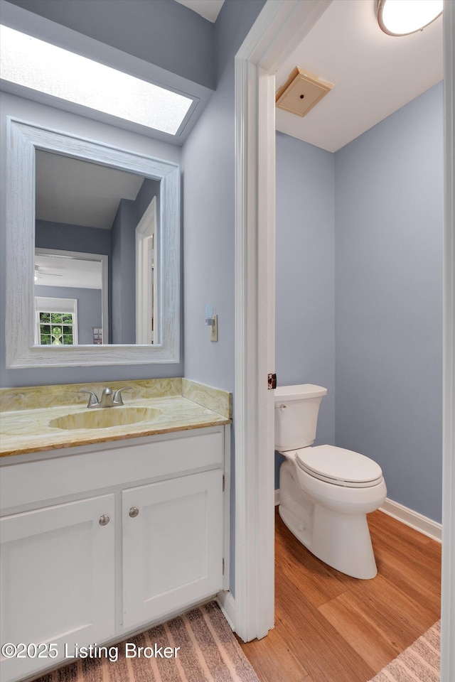 bathroom with wood finished floors, toilet, and vanity