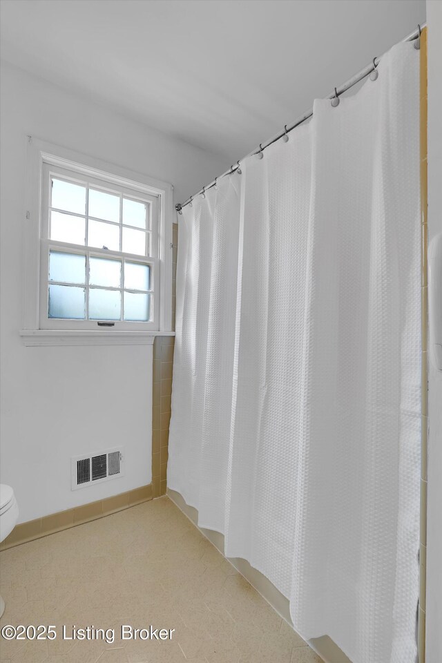 bathroom with toilet, visible vents, and curtained shower
