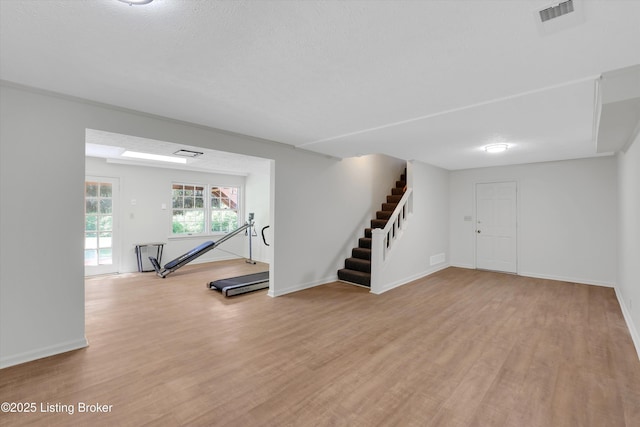 below grade area featuring baseboards, visible vents, stairway, and light wood-type flooring