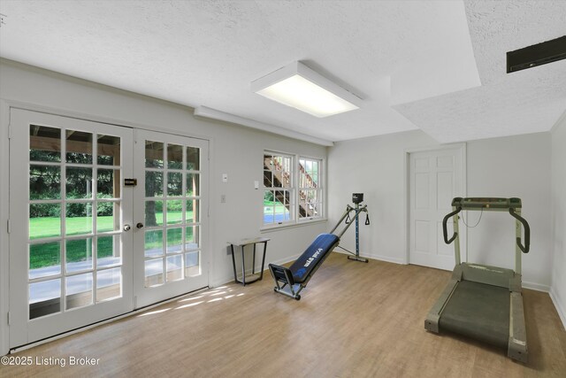 exercise area with a textured ceiling, wood finished floors, french doors, and baseboards