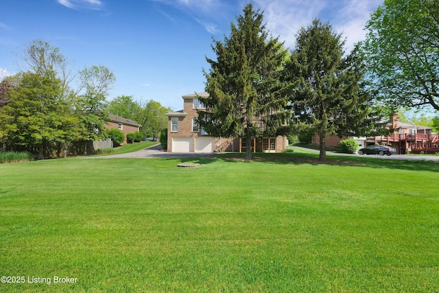 view of yard featuring driveway and a garage