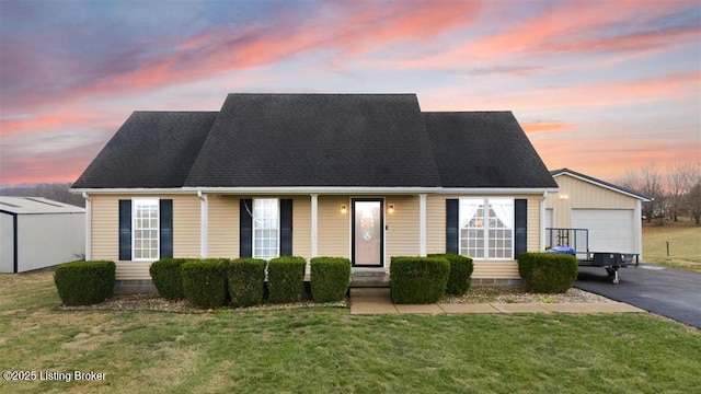 cape cod house featuring a garage, a yard, crawl space, and an outbuilding