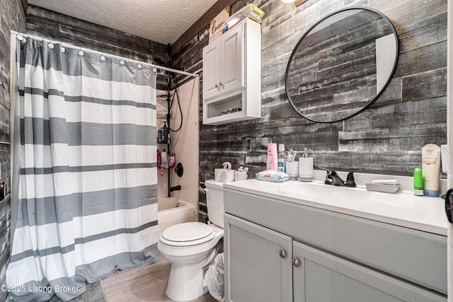 bathroom featuring wood walls, toilet, vanity, shower / tub combo, and a textured ceiling