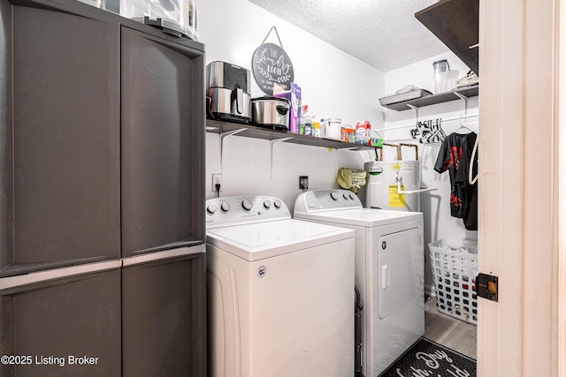 washroom with laundry area, water heater, a textured ceiling, washer and dryer, and wood finished floors