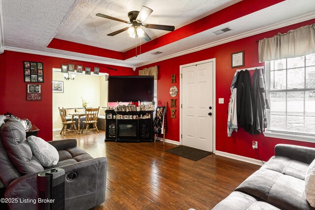 living area featuring wood finished floors, ceiling fan, a tray ceiling, and visible vents