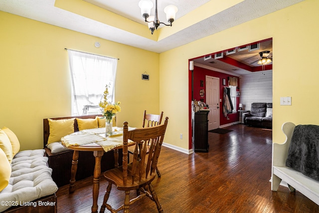 dining room featuring a raised ceiling, baseboards, ceiling fan with notable chandelier, and wood-type flooring