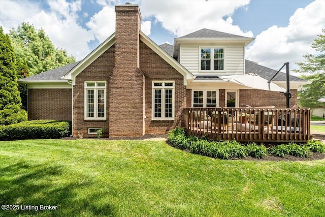 rear view of property featuring brick siding, a wooden deck, a yard, and a chimney