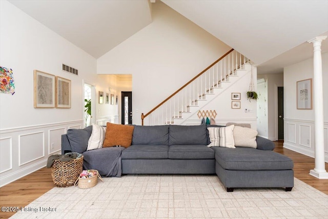 living area with visible vents, decorative columns, wood finished floors, and stairway