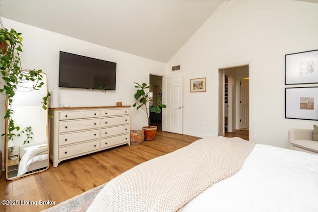 bedroom with visible vents, high vaulted ceiling, light wood finished floors, and baseboards