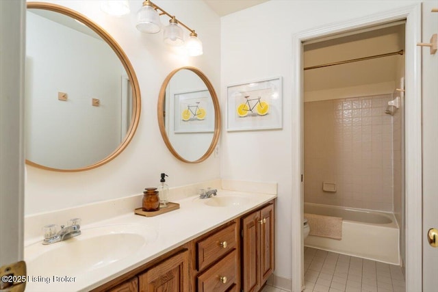 bathroom featuring toilet, double vanity, a sink, and tile patterned floors