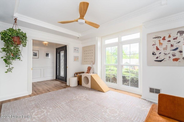 recreation room featuring visible vents, wood finished floors, a ceiling fan, and ornamental molding
