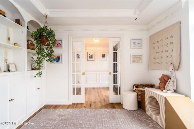 interior space featuring wood finished floors, french doors, and crown molding