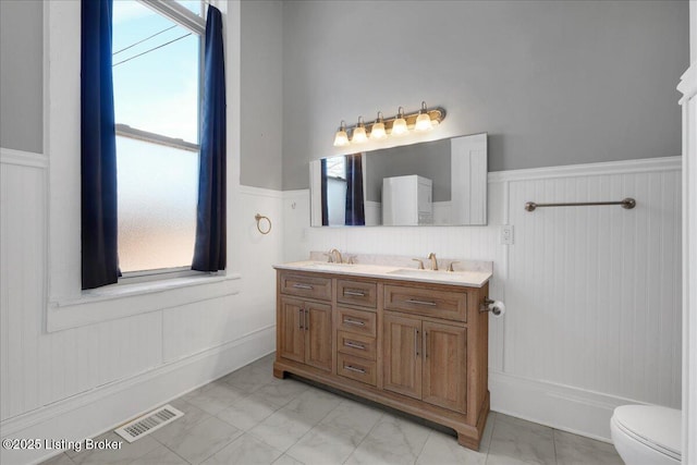 1460 S 6th St, Louisville, KY 40208 - bathroom featuring a sink, double vanity, visible vents, a wainscoted wall, and toilet