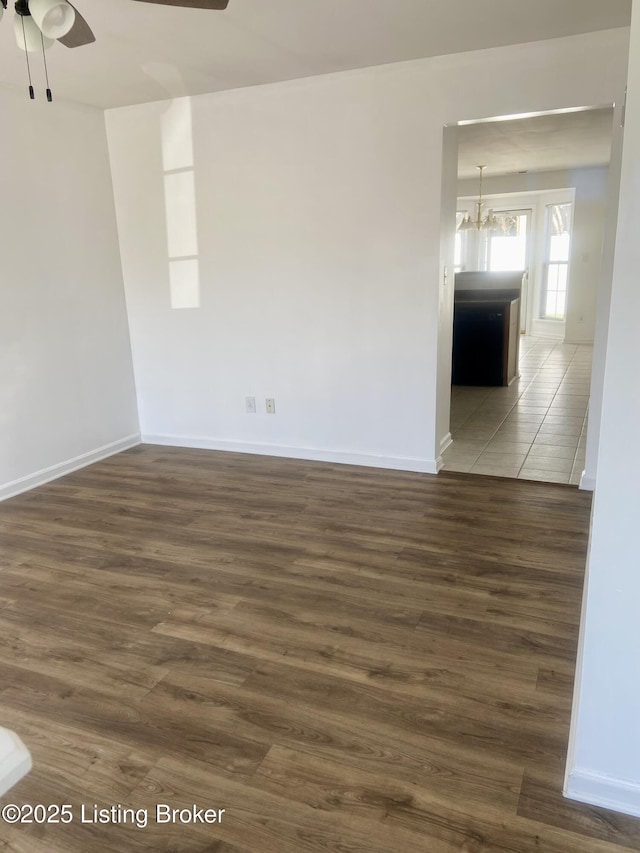 empty room with wood finished floors and ceiling fan with notable chandelier