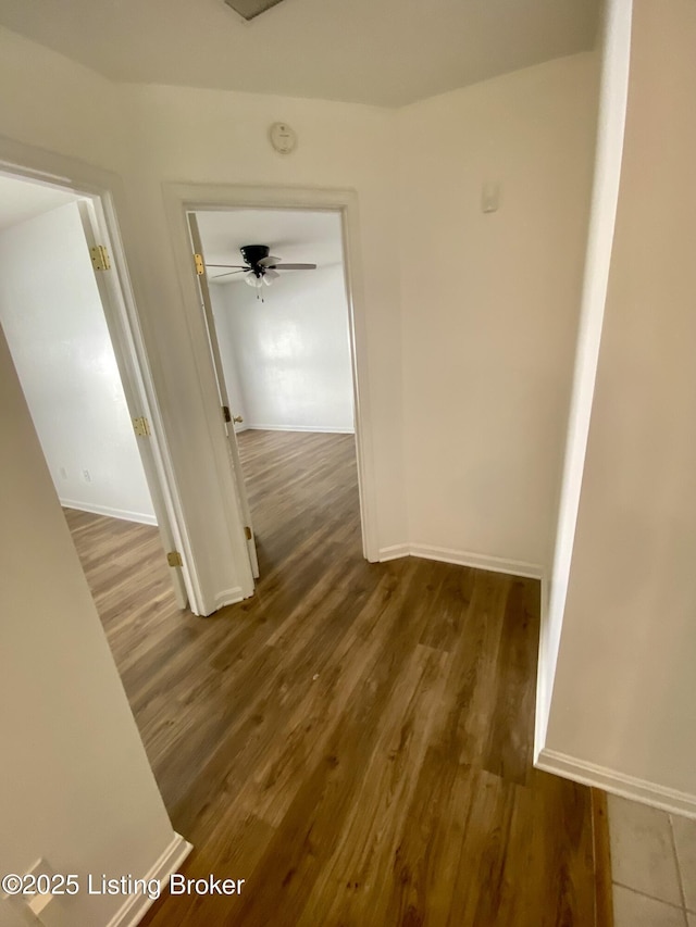 corridor with wood finished floors and baseboards