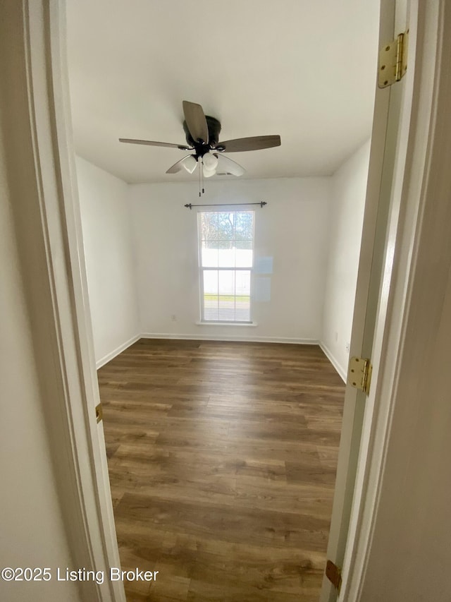 empty room with dark wood finished floors, baseboards, and a ceiling fan