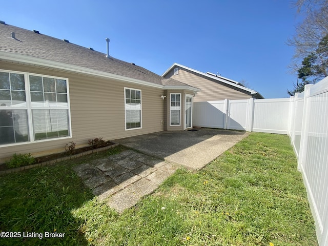 back of house with a lawn, a patio area, a shingled roof, and a fenced backyard