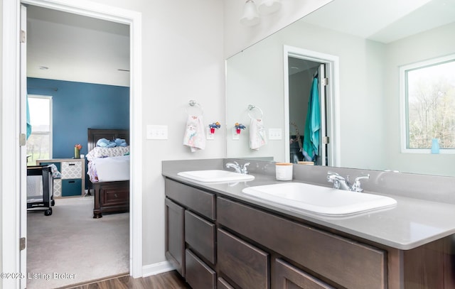ensuite bathroom featuring double vanity, a sink, wood finished floors, and ensuite bathroom