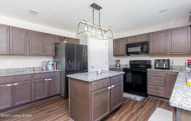 kitchen with black appliances, an inviting chandelier, a kitchen island, and dark wood finished floors