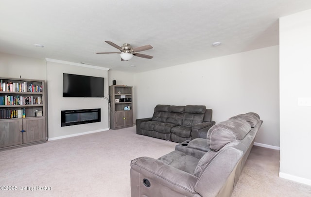 living area with a glass covered fireplace, ceiling fan, baseboards, and light carpet