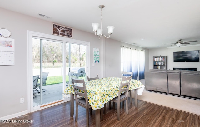 dining space featuring visible vents, ceiling fan with notable chandelier, and dark wood-style flooring
