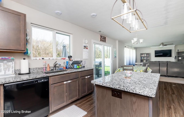 kitchen with a sink, open floor plan, light stone countertops, dishwasher, and dark wood finished floors
