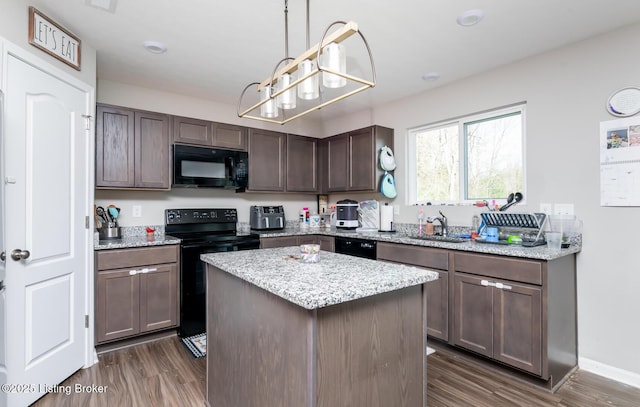 kitchen featuring black appliances, light stone counters, dark wood finished floors, and a center island
