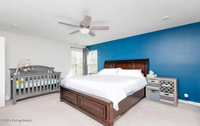 bedroom featuring light colored carpet, ceiling fan, and baseboards