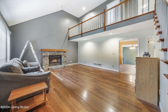 living room featuring visible vents, hardwood / wood-style floors, ceiling fan, a fireplace, and high vaulted ceiling