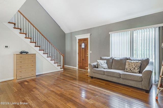 living area with baseboards, high vaulted ceiling, wood finished floors, and stairs
