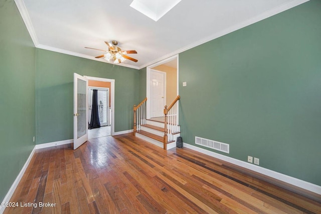 empty room featuring wood finished floors, visible vents, baseboards, and a skylight
