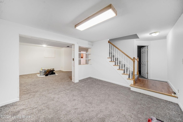 finished basement featuring carpet flooring, stairway, and baseboards
