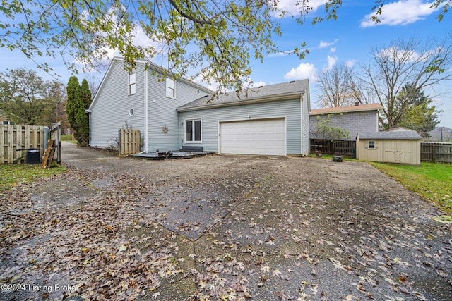 back of house with driveway, an outbuilding, a storage shed, an attached garage, and fence