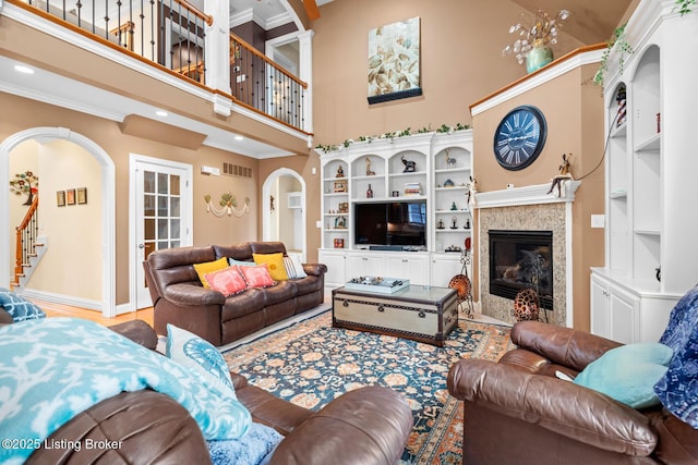14729 Forbes Cir, Louisville, KY 40245 - living room featuring crown molding, baseboards, arched walkways, a towering ceiling, and a tiled fireplace