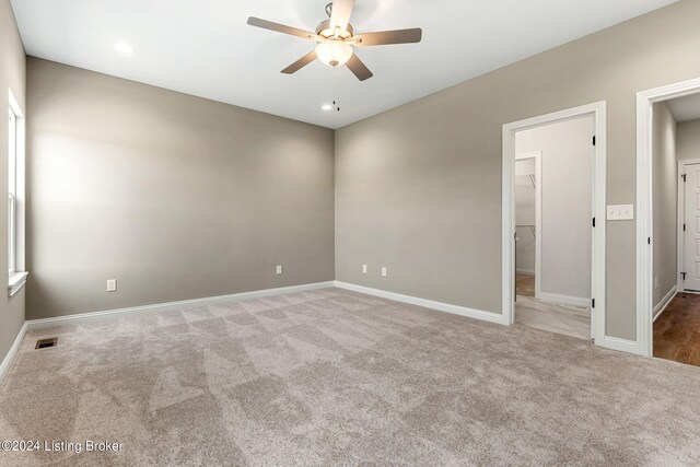 carpeted spare room featuring baseboards, visible vents, and ceiling fan