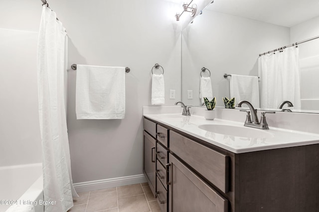 bathroom with baseboards, shower / bathtub combination with curtain, double vanity, and a sink
