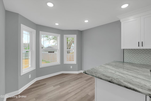 unfurnished dining area with recessed lighting, baseboards, and light wood-style floors