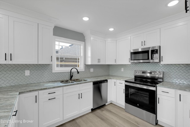 kitchen featuring appliances with stainless steel finishes, backsplash, white cabinets, and a sink