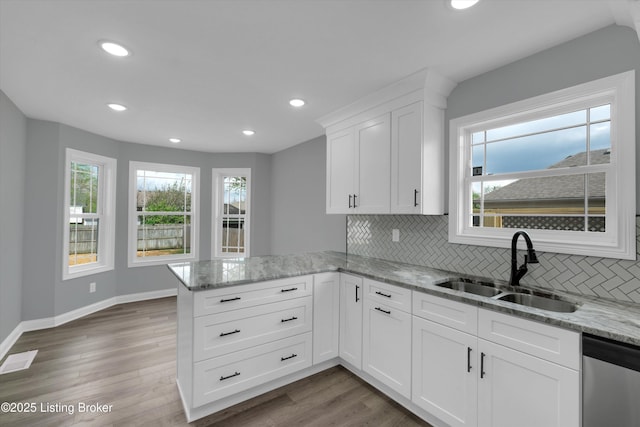 kitchen with recessed lighting, a sink, decorative backsplash, a peninsula, and stainless steel dishwasher