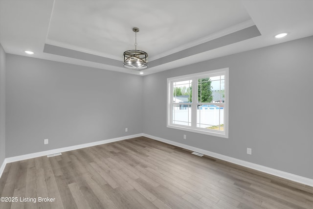 unfurnished room featuring wood finished floors and a tray ceiling