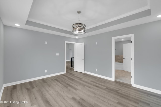 interior space with recessed lighting, baseboards, wood finished floors, and a tray ceiling