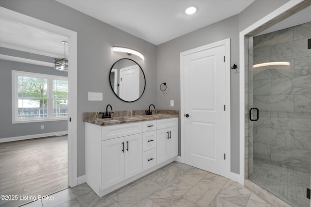 bathroom with a shower stall, a sink, double vanity, baseboards, and marble finish floor